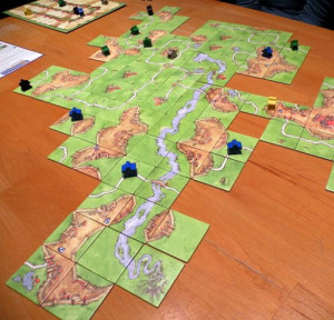 Tabuleiro do Carcassone montado com cartas como em uma partida de dominó