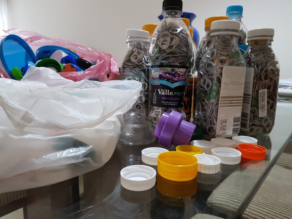 Recolhendo tampas plásticas e lacres para alimentar crianças carentes
