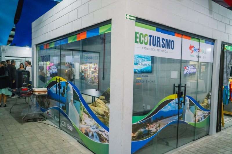 Espaço do Receptivo de Ecoturismo na Feirinha do Bem, em Bertioga, com painéis sobre atrações turísticas.